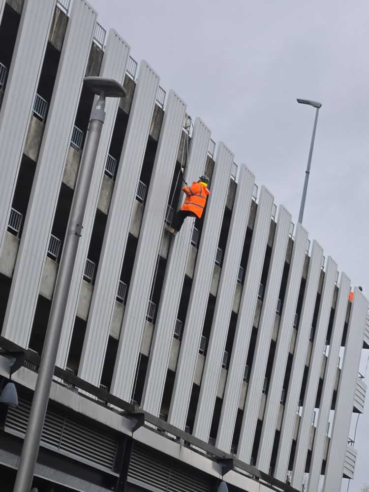 Roofmaster operative working at height inspecting cladding